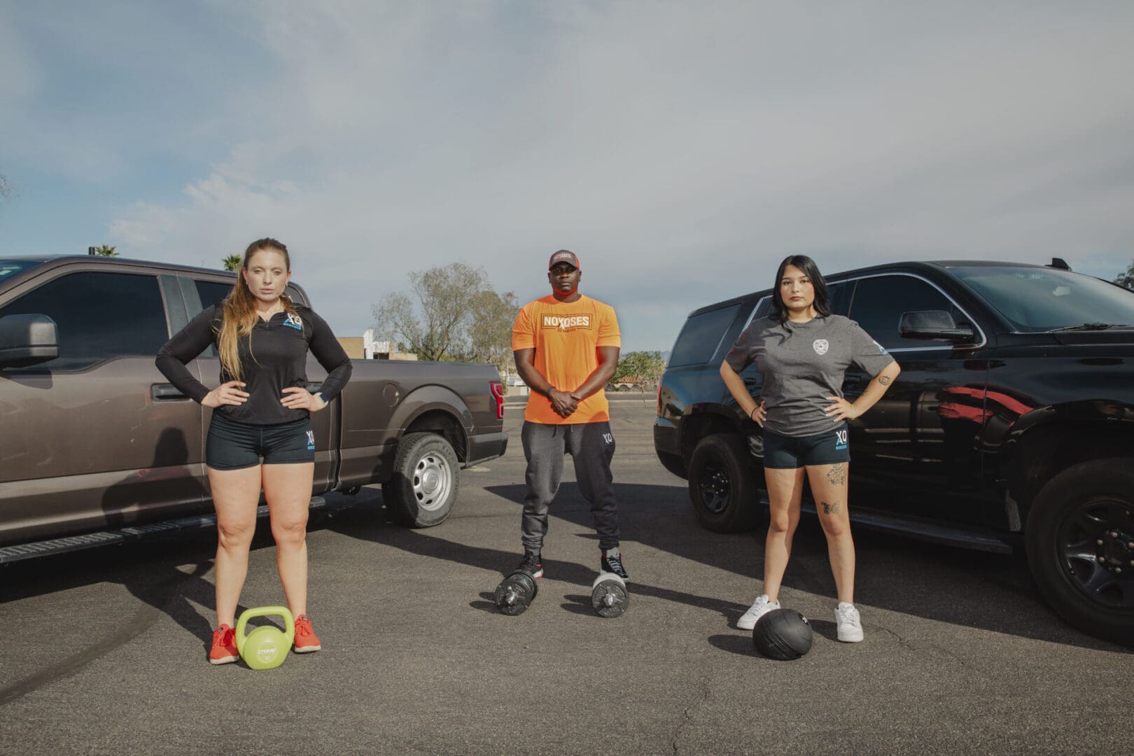 Three people standing with exercise equipment.